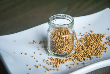 Healthy buckwheat grains in glass jar on white plate