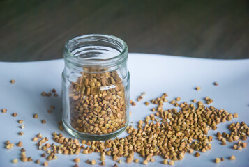 Healthy buckwheat grains in glass jar on white plate