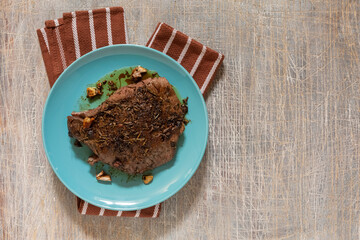 juicy steak with blood fried in a pan, top view, traditional food
