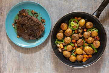 Large fried piece of ham meat in a pan with vegetables and spices, American lunch fried piece of meat and potatoes, beans in sauce and snacks, copy space for text