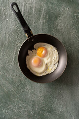 Ugly fried eggs in a frying pan, top view