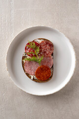 closeup sandwich with dried sausage, brown bread, butter