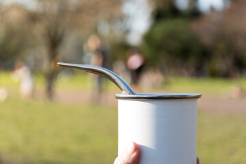 Hand holding a mate container, typical of South America, with its bombilla.