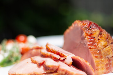 Partially carved cooked ham on a plate