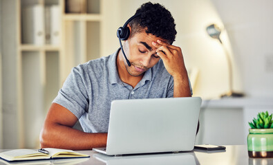 Stressed, tired and frustrated call center agent feeling sick or ill in the office while working on his laptop. A worried and unhappy young telemarketing employee suffering from a headache and pain