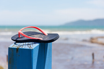 Footwear on top of a signpost at the beach on a sunny day.