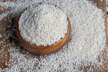 a large amount of white dried sesame seeds in a wooden bowl