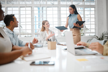 Female intern, assistant or employee handing out an information document to a team during a boardroom meeting. Group of business people discussing the mission, vision and strategy for company growth