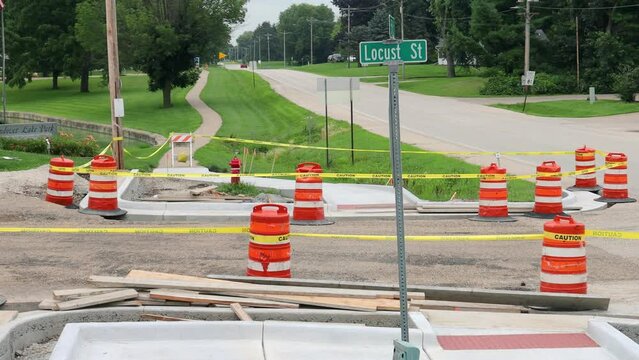 Pan of one of several state wide sidewalk, curb and gutter projects in small towns in Illinois; construction barrels barricade the work site to protect newly poured concrete