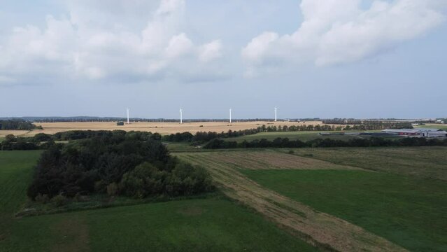 4 wind turbines on a meadow with beautiful clouds in the sky in the background, in denmark