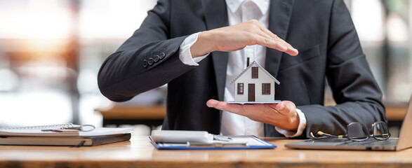 Property insurance and security concept. Businessmen use hands to protect the house model, gestures...