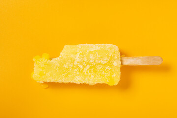 top view orange color popsicle with some bites on an orange color background