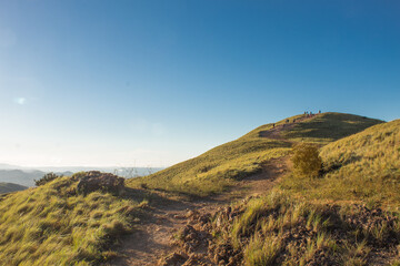 Fototapeta premium landscape with green mountains with people on the top and blue sky in a sunny morning