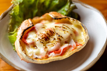 こんがり焼けたチーズが食欲をそそるカニの甲羅グラタン、カニの身が詰まった贅沢なシーフード料理の盛り付け | Roasted Crab Shell Gratin with Melted Cheese and Succulent Crab Meat, Gourmet Seafood Dish on a Plate
