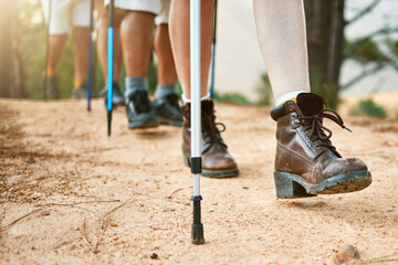 . Group of hikers hiking with walking sticks on a trail outdoors in nature for fitness. Fit, active...