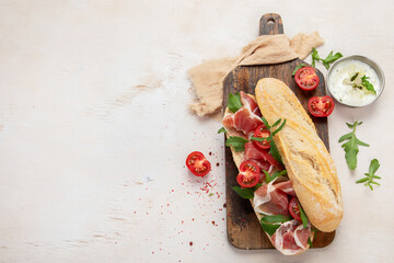 Fresh crispy baguette deli sandwich with prosciutto, tomatoes and arugula.