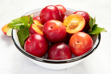 Naklejka na ściany i meble Plate of fresh ripe plums on table.