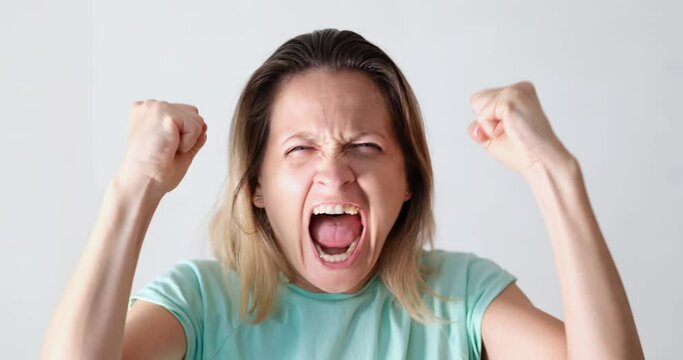 Portrait of beautiful young caucasian woman screaming in anger directly at camera