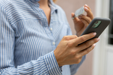 female hands hold a modern mobile phone and a bank credit or debit card on the street..ordering purchases, working online, transferring money by phone