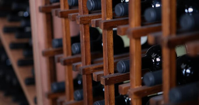 Worker arranges wine bottles in container or wooden box in wine cellar