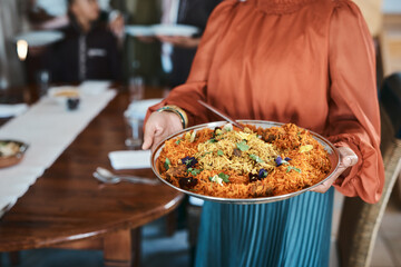 Food, dinner and consumables with a traditional paella dish in the hands of a woman at home....