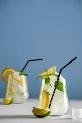 Mojito with ice, summer refreshing cocktail with lime and mint, cold drink with alcohol and ice, on a light blue background, space for text 