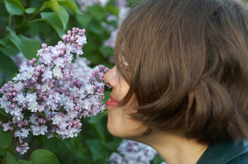 Naklejka premium Close up portrait of beautiful woman smelling purple lilac