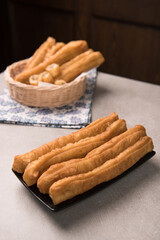 Cakwe or You tiao is a long golden-brown deep-fried strip of dough or typical chinese doughnut. Served in bamboo woven plate