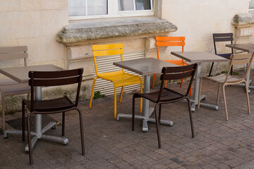 metal chairs and tables in the street facing the restaurant bar terrace in street