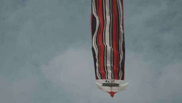 Balinese Traditional Kites JANGGAN (Red White Black Long Tail Bird Dragon) on Bali Kite Festival Summer Blue Sky Slow Motion