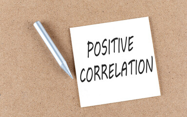 POSITIVE CORRELATION text on a sticky note on cork board with pencil