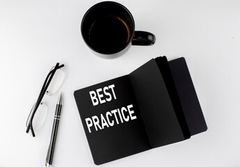 Naklejka premium BEST PRACTICE written text in small black notebook with coffee , pen and glasess on white background. Black-white style