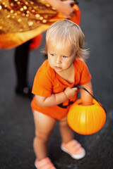 Fototapeta premium Lifestyle portrait of Happy Little caucasian siblings with blonde hair in black orange costume of which celebrating Halloween together outdoor