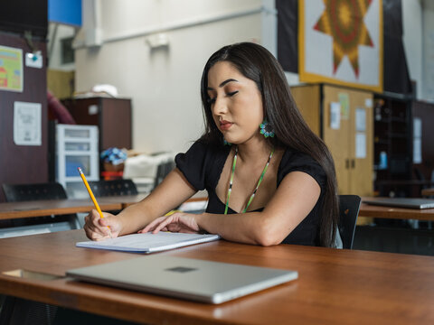 Native girl looks down at notebook with a concentrated face
