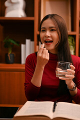 Beautiful Asian businesswoman taking a vitamin to refresh herself after had a long day at work.