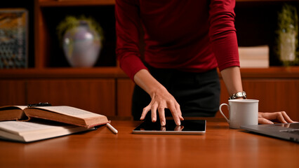 Fototapeta na wymiar Professional businesswoman or project manager standing leaned at her office desk and using tablet.