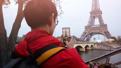 Selective focus of man hand with he is using smartphone take photo at View on Eiffel Tower, Paris, France