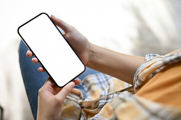 Top view, A smartphone white screen mockup is in a hipster woman's hands. close-up