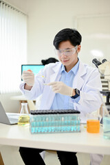 Portrait, Smart Asian male scientist using a dropper tube to adjust specimen on a Petri dish.