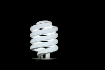 Glowing spiral light bulb isolated on dark background. Eco energy saving light bulb concept