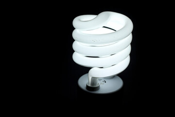 Glowing spiral light bulb isolated on dark background. Eco energy saving light bulb concept