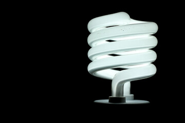 Glowing spiral light bulb isolated on dark background. Eco energy saving light bulb concept