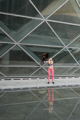 Young woman stretching in front of glass building to warm up for exercise