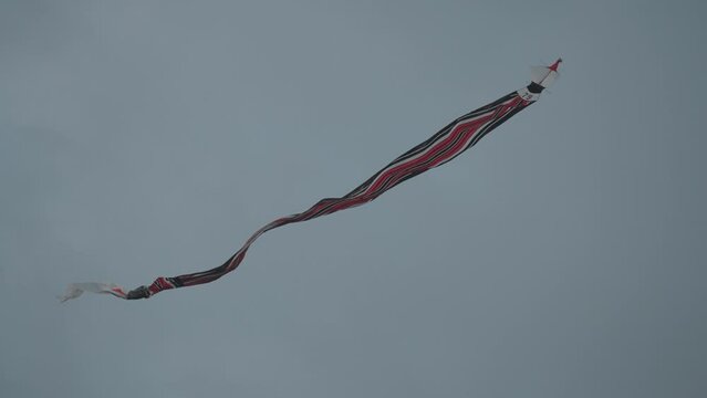 Balinese Traditional Kites JANGGAN (Red White Black Long Tail Bird Dragon) on Bali Kite Festival Summer Blue Sky Slow Motion