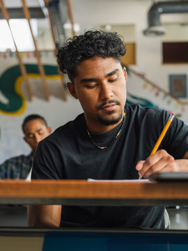Low angle of a Native student with curly hair writing in school
