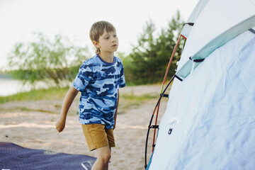 cute little caucasian boy helping to put up a tent. Family camping concept