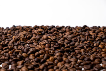 Fototapeta na wymiar A scattering of coffee beans on a white background with space for text.
