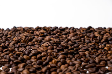 A scattering of coffee beans on a white background with space for text.