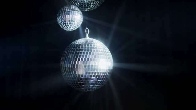 Disco Ball with Reflected Moving Rays Rotating. Mirror disco ball in white light. Isolated disco ball on black background. Close-up. Mirror ball spinning indoors. Performance. The reflection of lights
