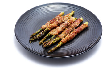baked aspargus covered with bacon on ceramic plate isolated on white background